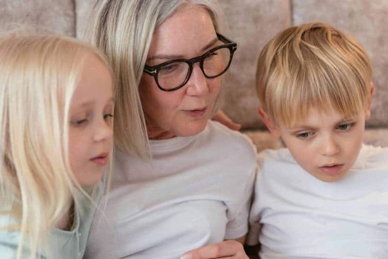 A grandmother and her grandchildren enjoy quality time together indoors.